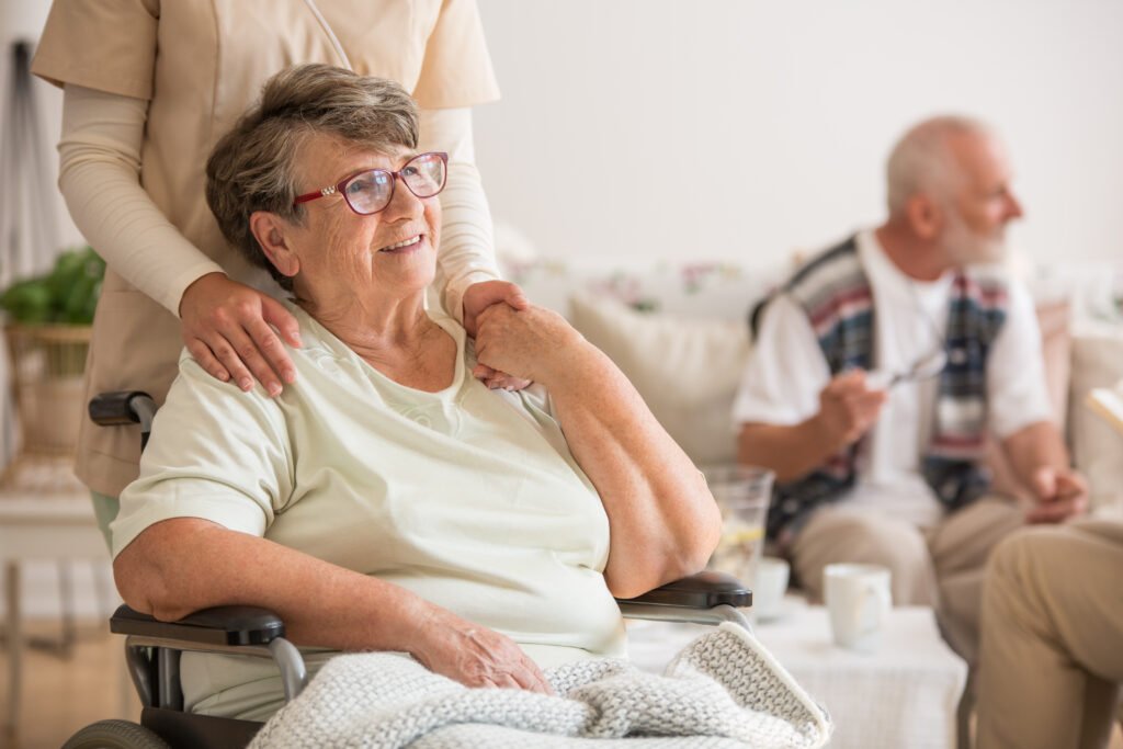 Ältere Dame im Rollstuhl lächelt, während die Krankenschwester einfühlsame Unterstützung bei Deutsches Pflegehilfswerk bietet.