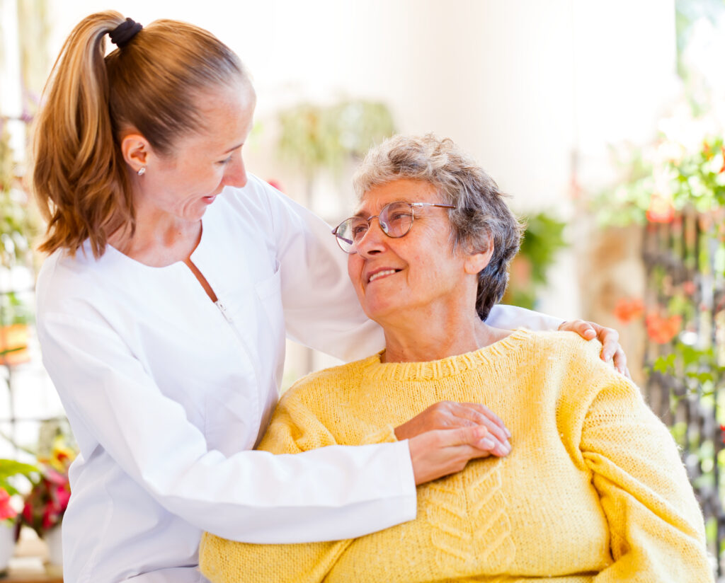 Pflegekraft hält die Hand des Seniors, teilt ein Lächeln und einen warmen Blick.